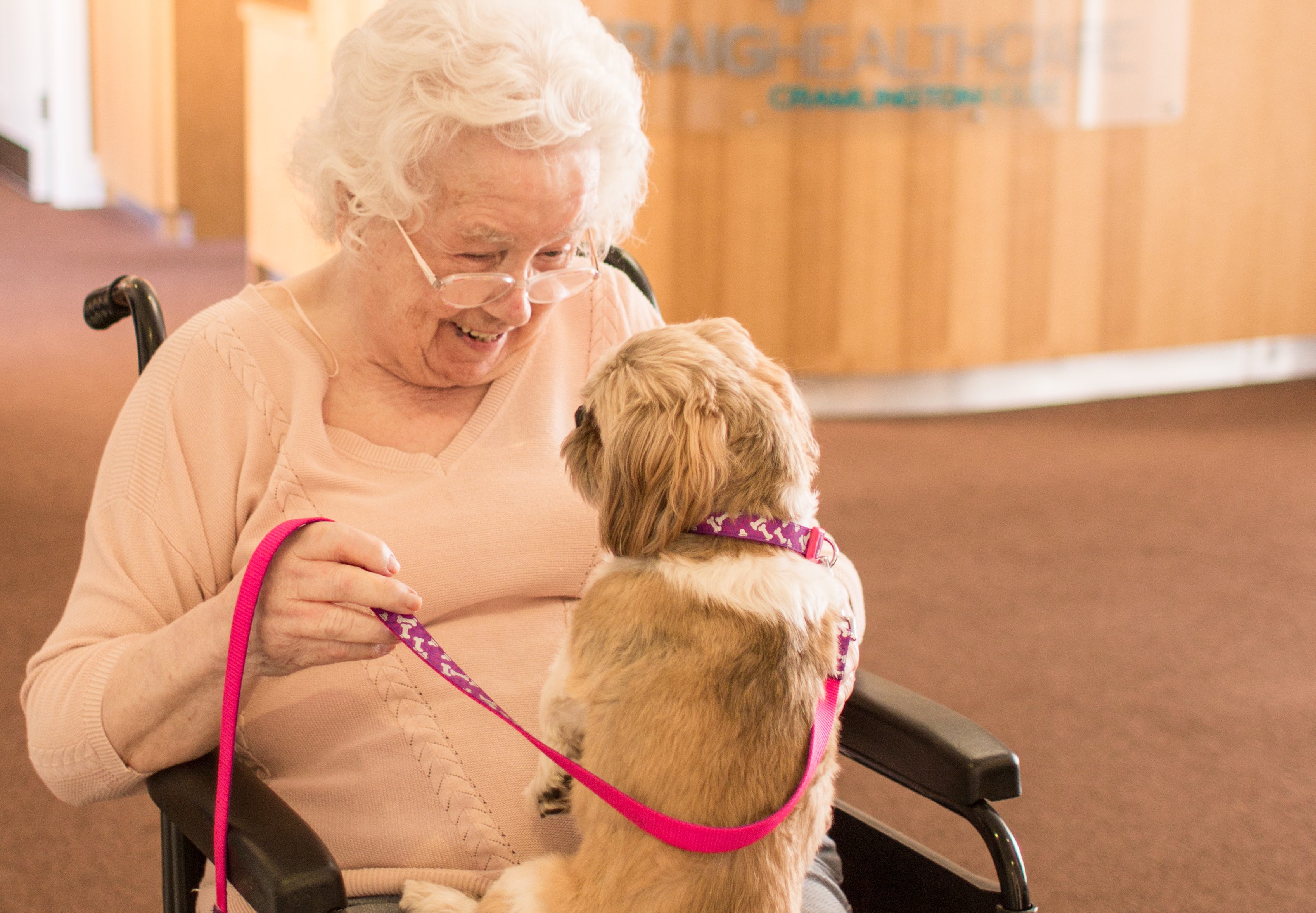 Craig Healthcare puppy and resident smiling